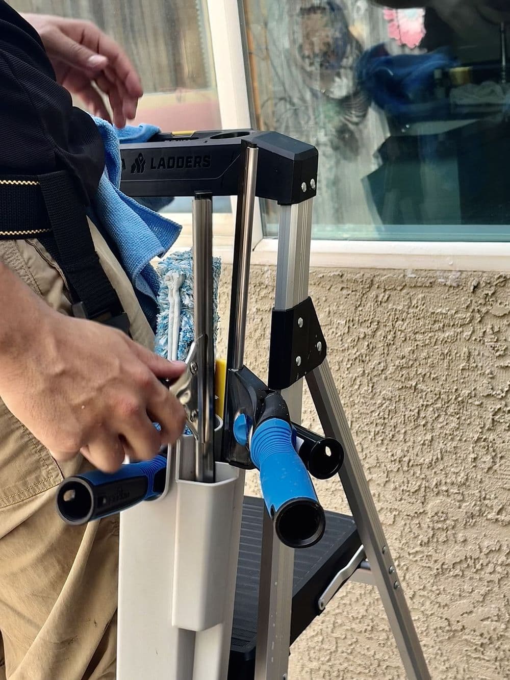 Hand adjusting tools on a ladder with a focus on a work project.