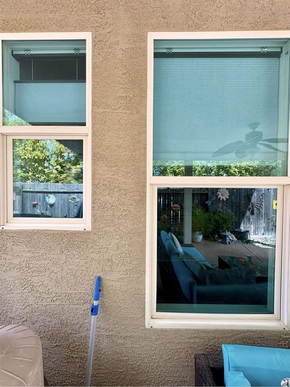 Two windows on a textured wall, showcasing a view of a patio with furniture and greenery.