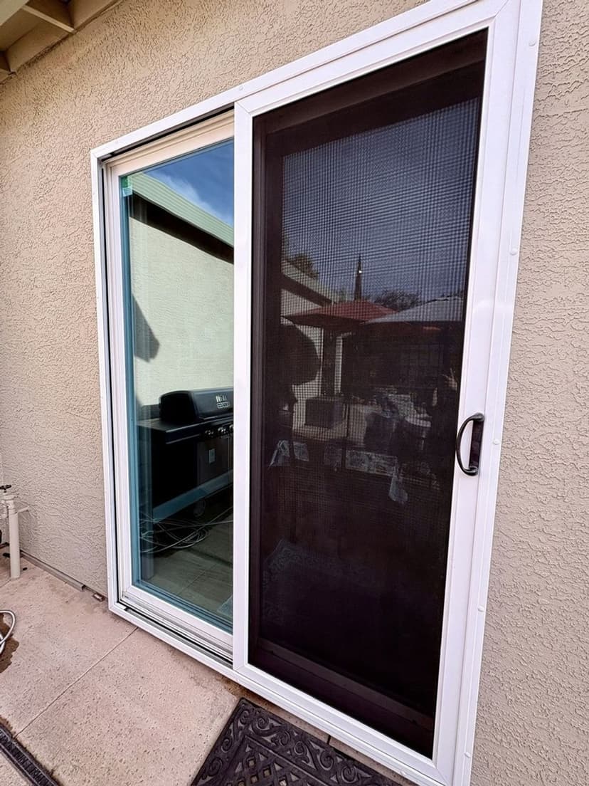 Sliding glass door with a black screen, revealing outdoor patio view.